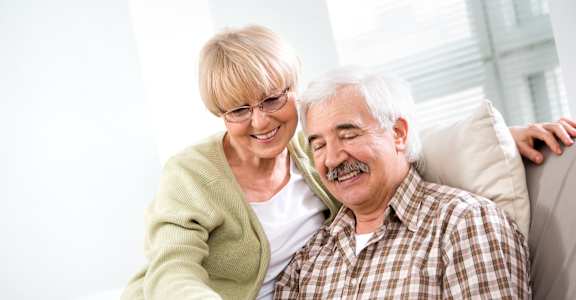 An elderly man and woman are looking at a tablet together.