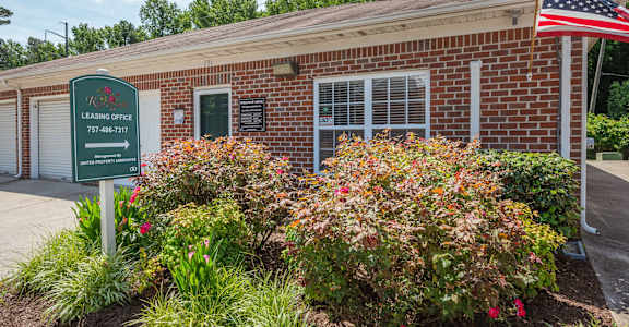 the outside of a brick building with a sign and flowers