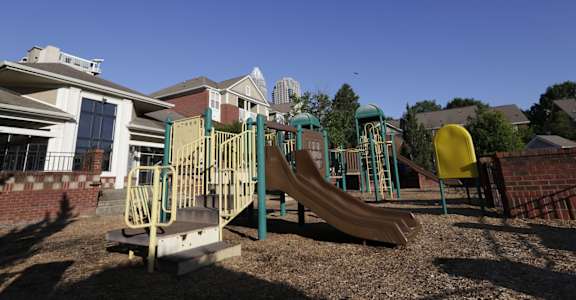 A playground with a yellow slide and green and blue play structures.