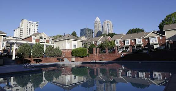 A pool in a residential area with a city skyline reflected in the water.