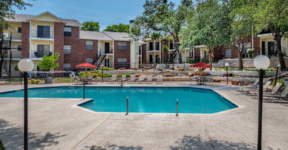 A swimming pool surrounded by apartment buildings and trees.