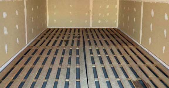 A room with wooden flooring and walls covered in insulation material.