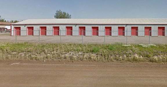 A long building with red doors is surrounded by a fence.