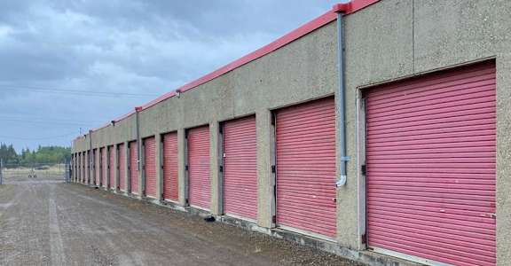 A long row of red garage doors on a concrete building.