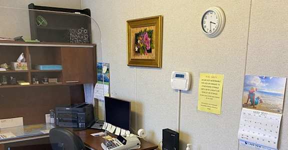 A small office with a desk, chair, and a clock on the wall.