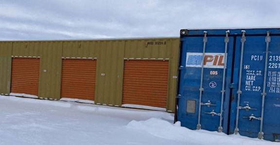 A blue shipping container with PIL written on it is in the snow.