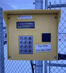 a yellow parking meter in front of a fence