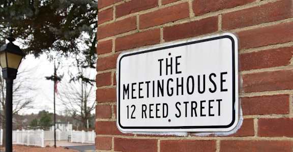 a sign for the meetinghouse 12reed street on a brick wall