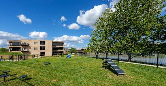 a grassy area with benches and trees in front of a building