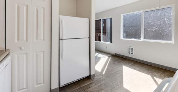A white refrigerator is in a kitchen with a white door.