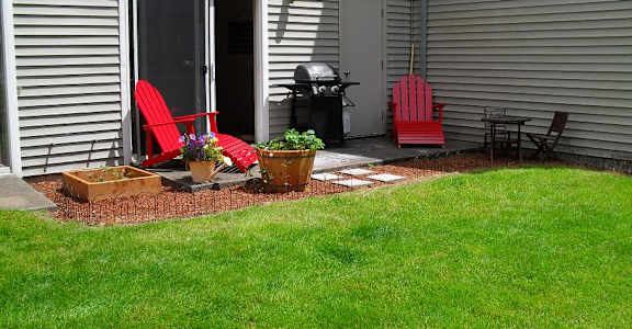two red chairs sitting in front of a house