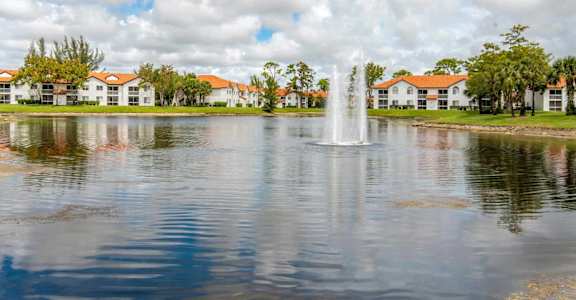 a fountain in the middle of a lake with houses in the background at The Villas at Ibis Landing, Florida, 33067