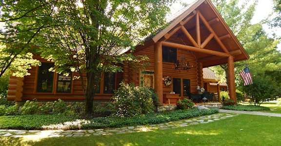 a large log cabin with a large lawn in front of it