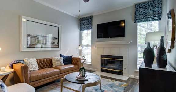 A living room with a brown couch, a fireplace, and a painting on the wall.