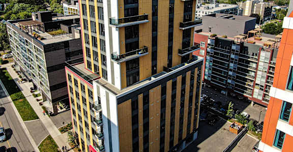 A tall building with a red top stands out against a cityscape.