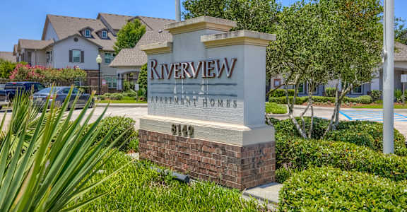 A sign for Riverview Homes stands in front of a residential area.