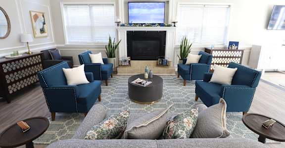 a living room with blue couches and chairs and a fireplace