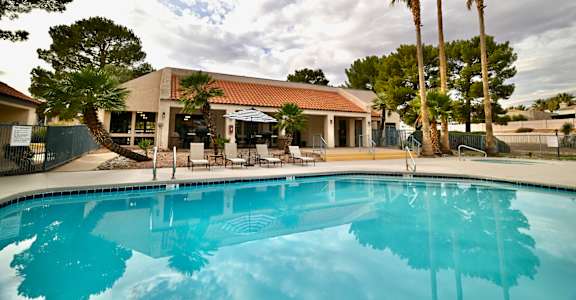 A swimming pool in front of a building with palm trees.