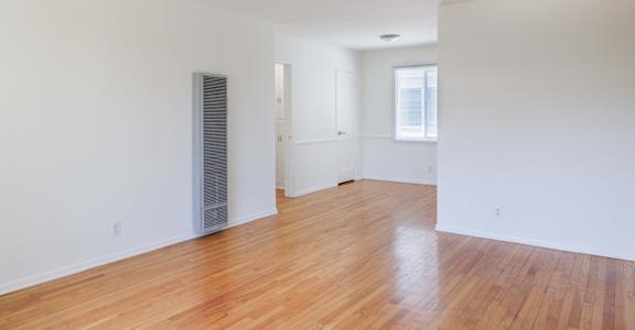 an empty living room with wood floors and white walls