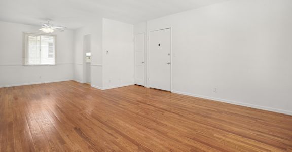 the living room of an apartment with wood floors and white walls