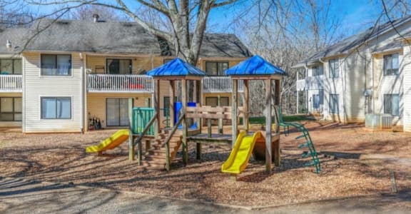 a playground with a swing set and slides in front of houses