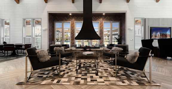 A modern living room with a black and white checkered rug and a large black fireplace.
