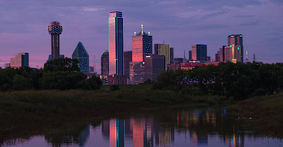 A city skyline is reflected in a body of water.