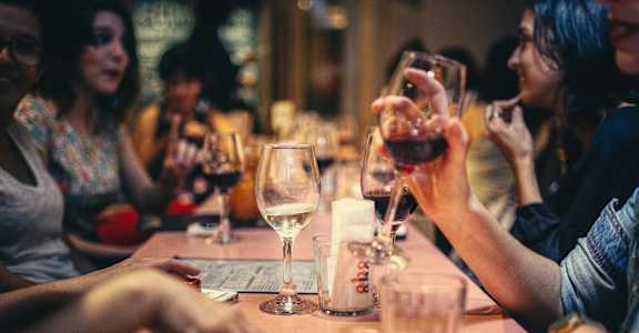 a group of people sitting around a table with wine glasses