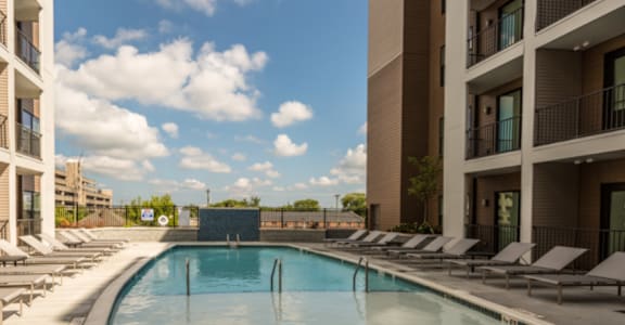 a swimming pool with chaise lounge chairs in front of a building