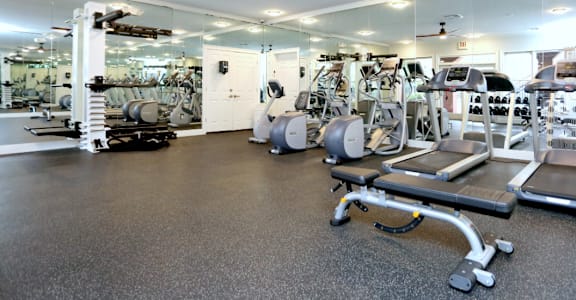a gym with cardio equipment and a ceiling fan