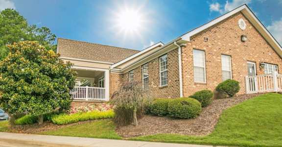 a brick house with green grass and bushes in front of it