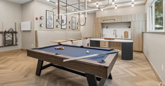 A pool table is in the middle of a room with a wooden floor.