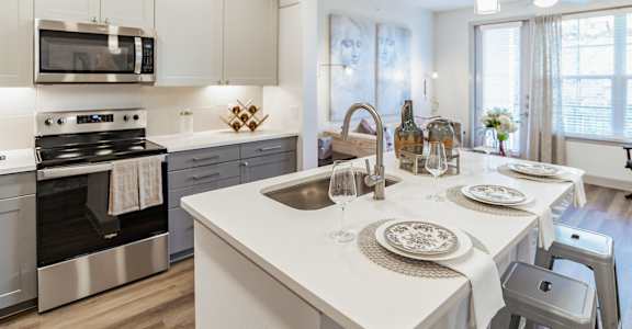 A modern kitchen with a white countertop and stainless steel appliances at Alys Crossing Apartments, Texas