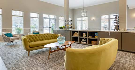 A living room with a yellow sofa and a grey carpet at La Veranda at La Veranda at Polly Lane Apartments, Louisiana