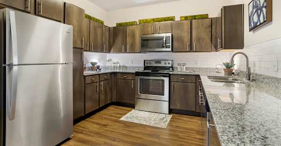 A kitchen with a stainless steel refrigerator and wooden cabinets at La Veranda at La Veranda at Polly Lane Apartments, Lafayette