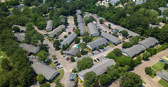 A bird's eye view of a parking lot surrounded by buildings and trees at Lakeshore Landing Apartments, Ridgeland, 39157