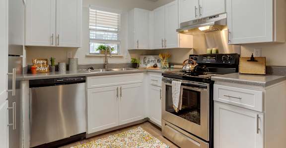 A kitchen with white cabinets and a patterned floor mat at Lakeshore Landing Apartments, Mississippi, 39157