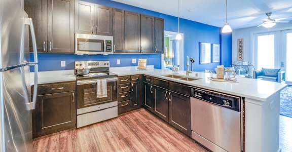 A modern kitchen with stainless steel appliances and wooden cabinets at Waterstone at Hamburg Apartments, Kentucky