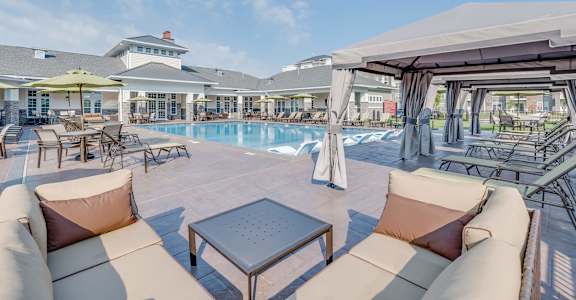 A patio with a table and chairs overlooking a pool at Waterstone at Hamburg Apartments, Kentucky, Lexington