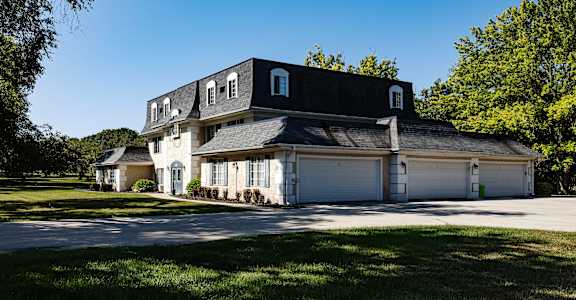 a white house with a black roof and white garage doors