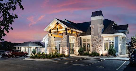 the facade of a hotel at sunset with a parking lot