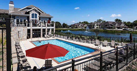 a pool with a red umbrella in front of a house
