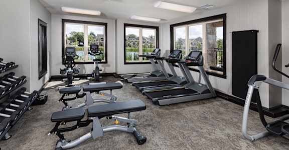 a gym with cardio equipment and windows in a building