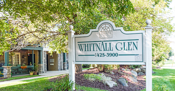 a white sign in front of a yard with a house