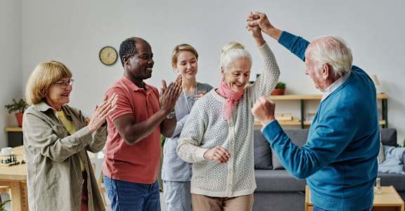 a group of seniors giving each other a high five in a living room at 55+ FountainGlen Stevenson Ranch, Stevenson Ranch, 91381