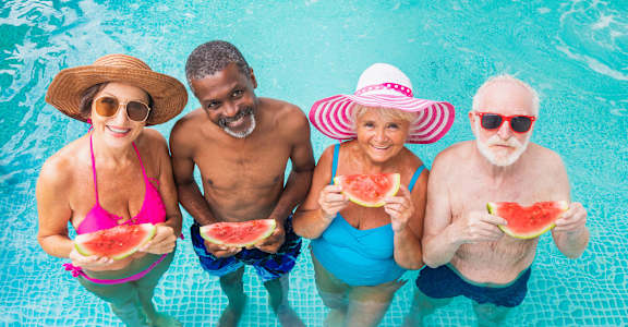 people in a pool eating watermelon and wearing hats and sunglasses at 55+ FountainGlen Temecula, Temecula, California