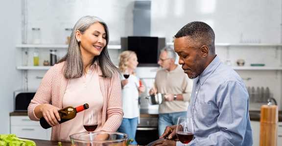a man and woman in a kitchen preparing food with a bottle of wine  at 55+ FountainGlen Terra Vista, Rancho Cucamonga, California
