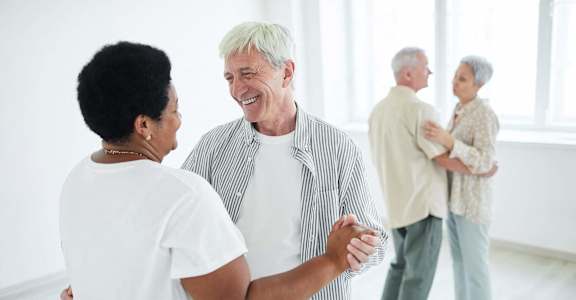 an older man shaking hands with a woman in a room  at 55+ FountainGlen Terra Vista, Rancho Cucamonga, CA