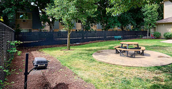 a fire pit and picnic table in the back yard of an apartment complex
