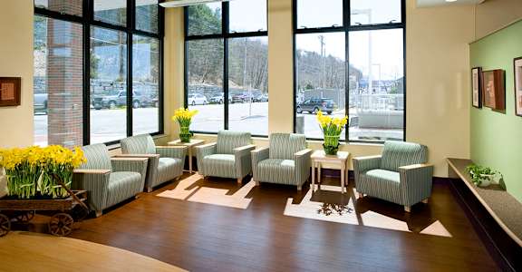 A waiting room with white chairs and a table with flowers on it.
